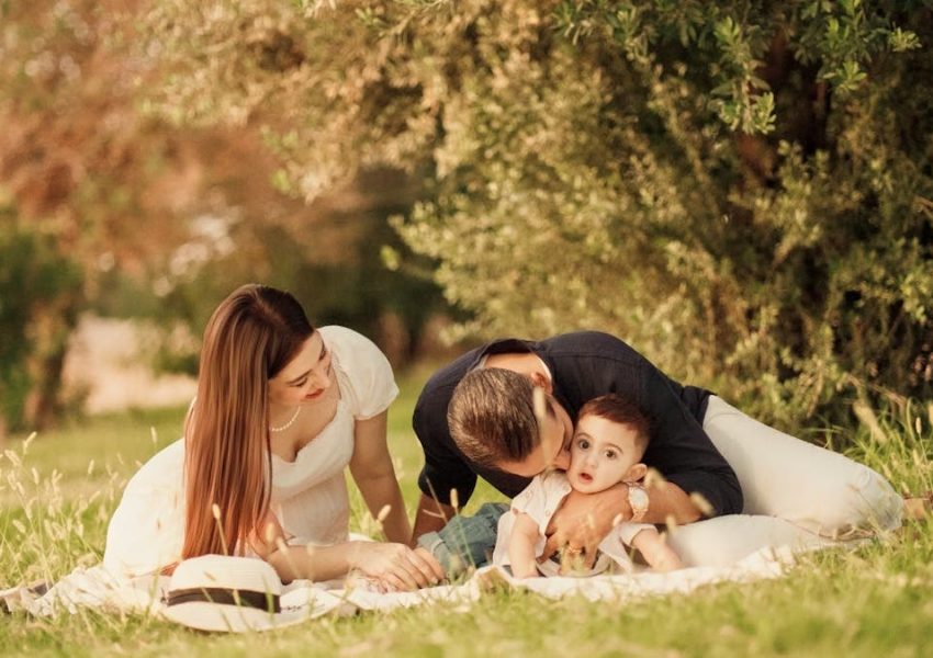 A happy family having a picnic in a lush green park setting during the day.