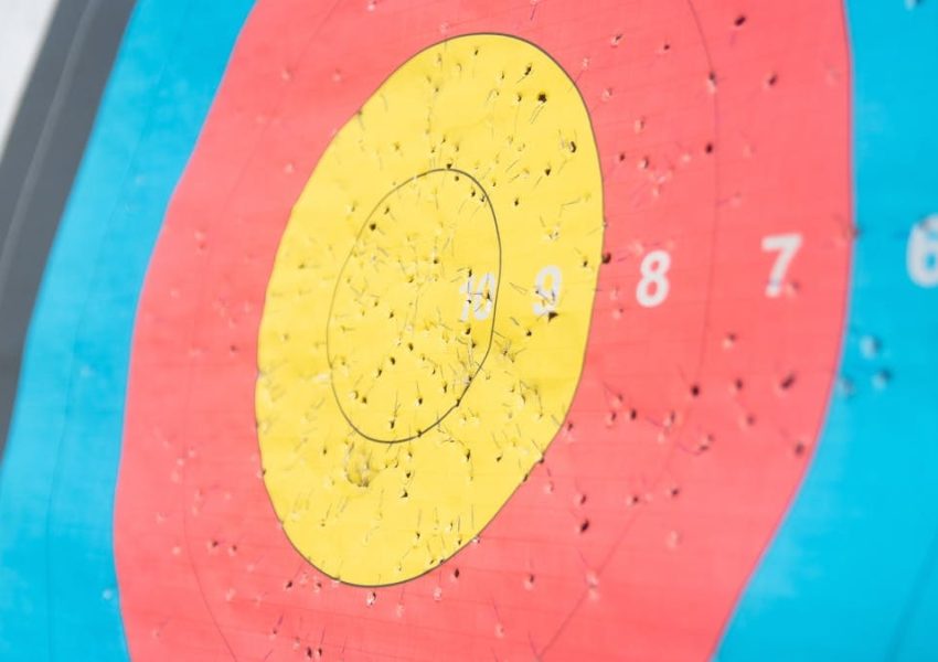 Detailed view of a colorful archery target with numerous arrow holes, showcasing precision